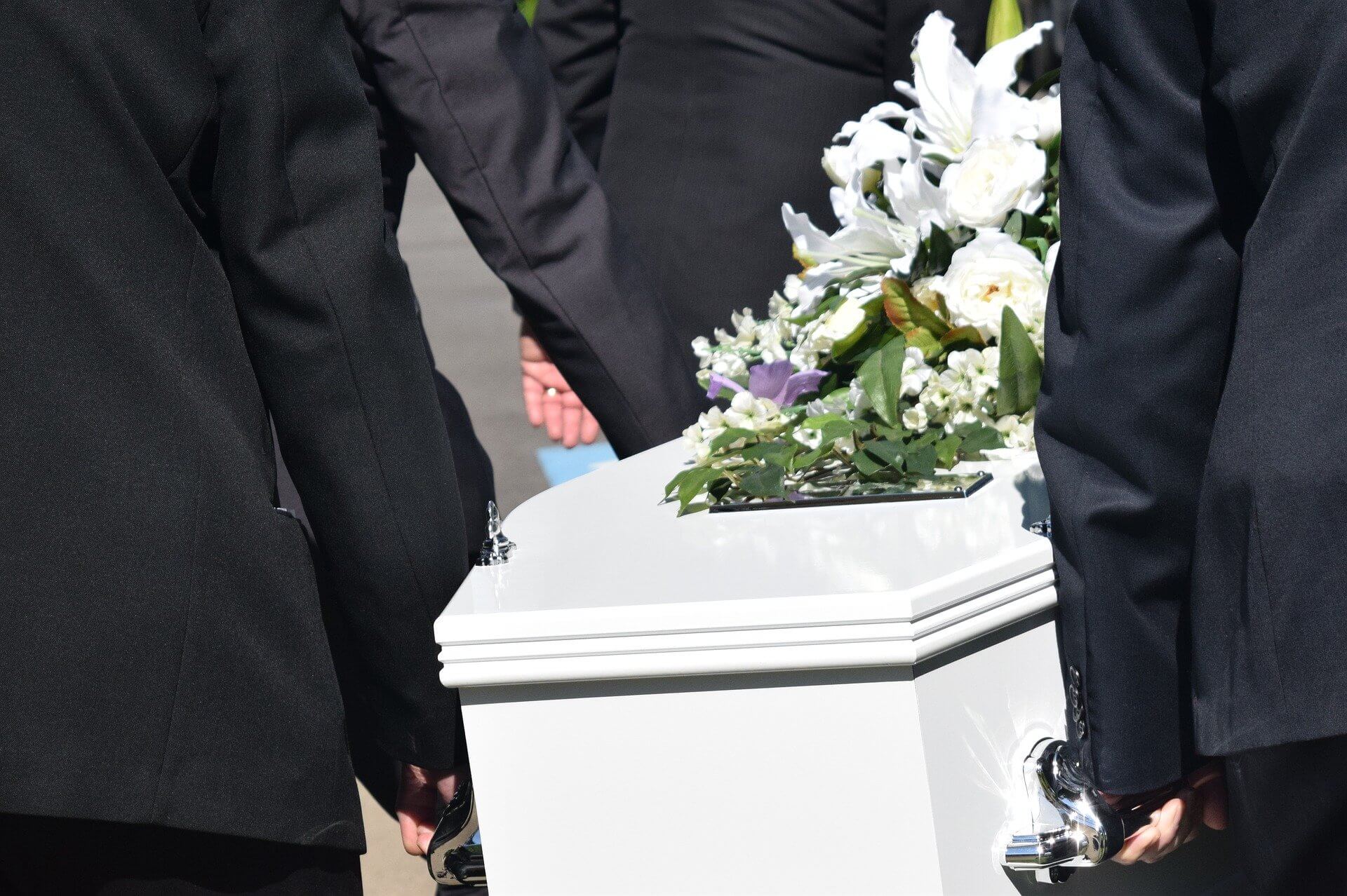 Sargträger tragen einen weißen Sarg bei Bestattungszeremonie von Bestattungen Männer